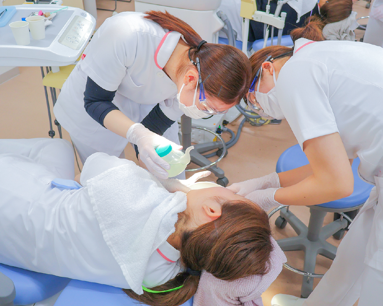 寝たままの姿勢で口腔洗浄するために「吸い飲み」を使っているところ。